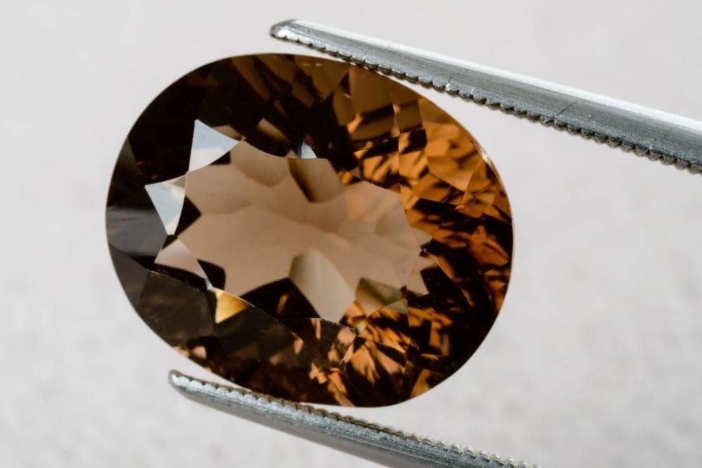Oval Smoky Quartz held in tweezers